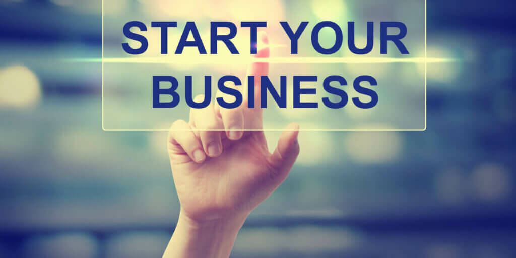 Hand pressing Start Your Business on blurred cityscape background